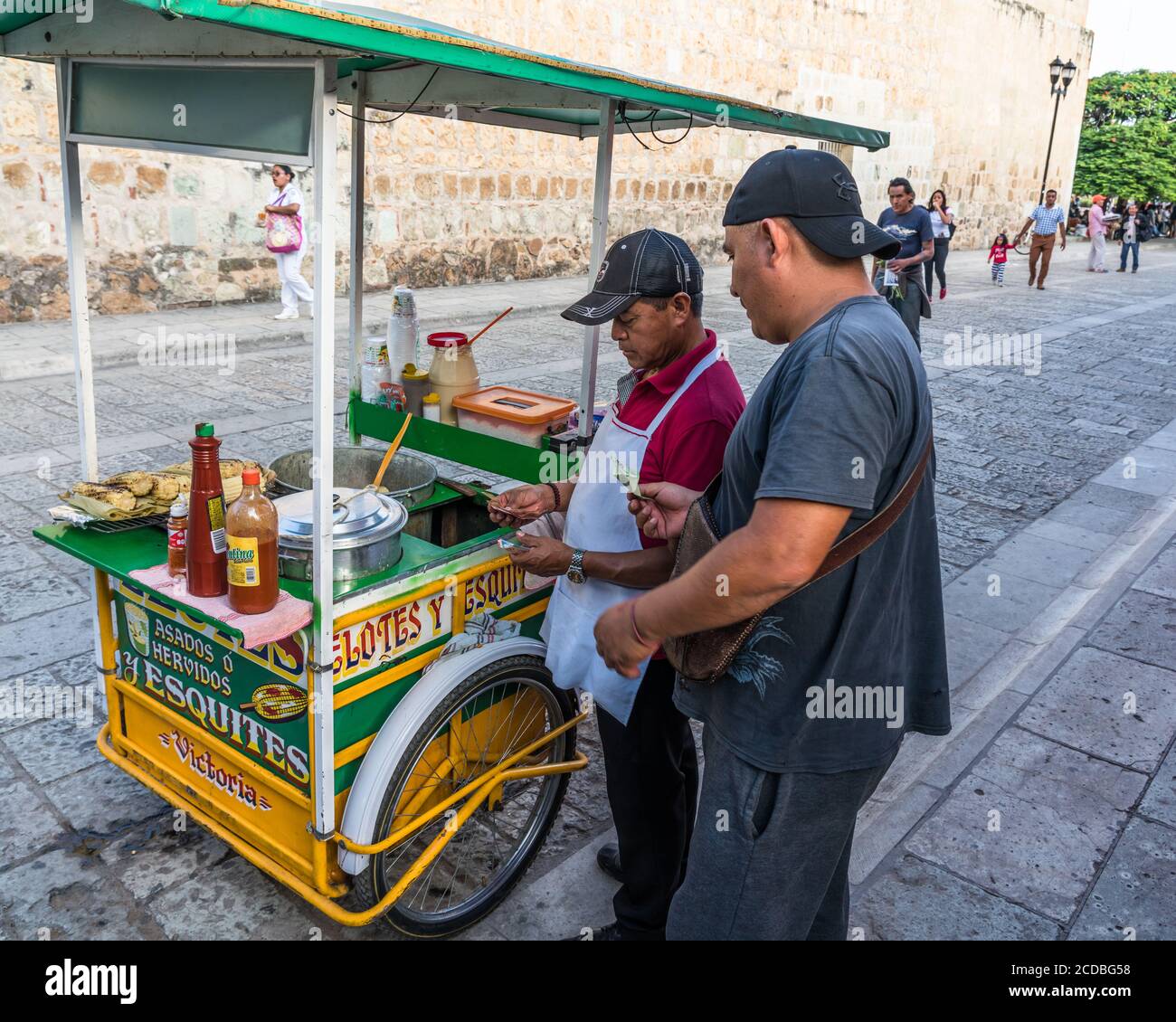 Un vendeur vendant des élotes et des esquites dans la rue du centre historique d'Oaxaca, au Mexique. Les Elotes sont du maïs sur l'épi qui sont d'abord bouillis, alors Banque D'Images