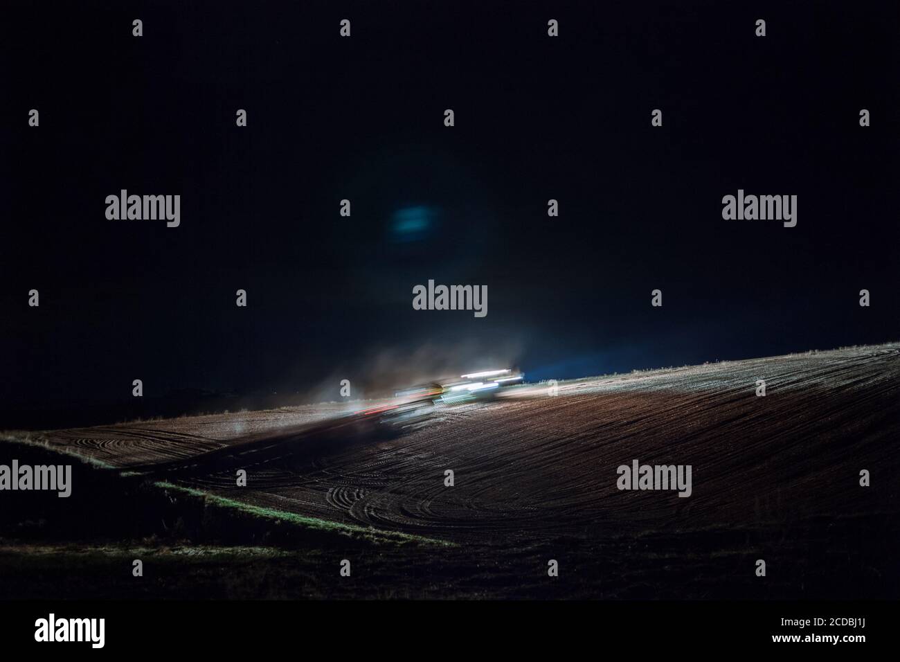 Agriculteur travaillant le champ de nuit avec un tracteur John Deere. Banque D'Images