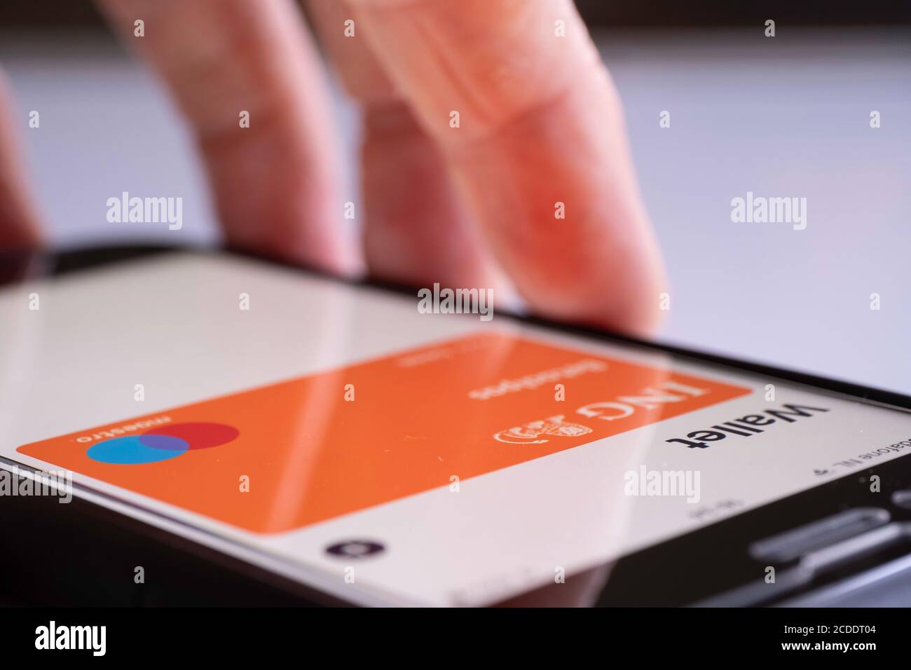 Tient à la main iPhone prêt à payer avec le portefeuille Apple Pay. Carte de débit ING néerlandaise dans le portefeuille Banque D'Images
