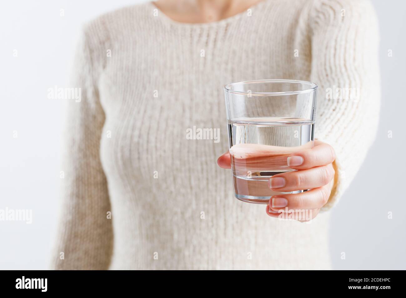 Une femme tient un verre d'eau dans ses mains. Banque D'Images