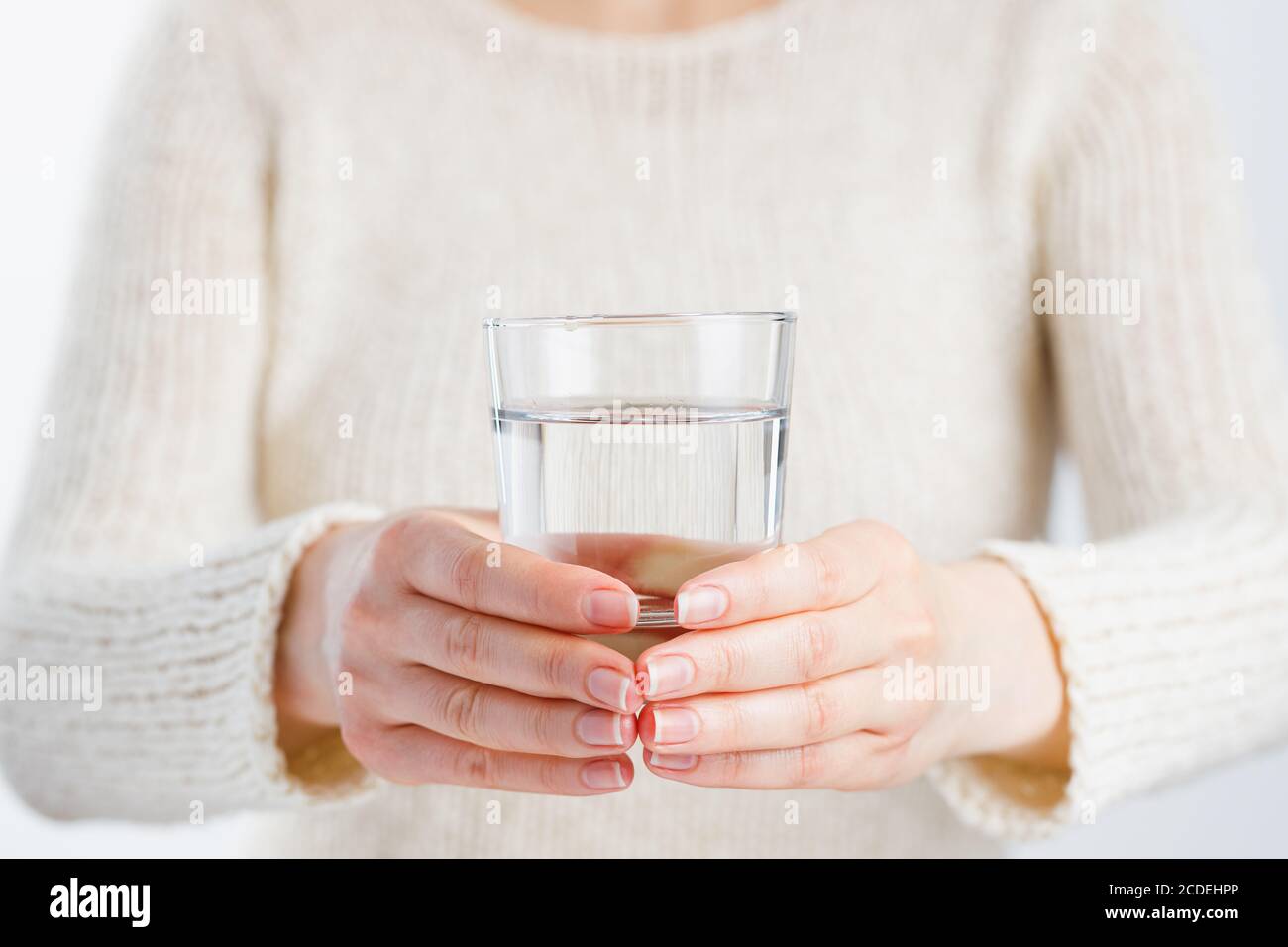 Une femme tient un verre d'eau dans ses mains. Banque D'Images