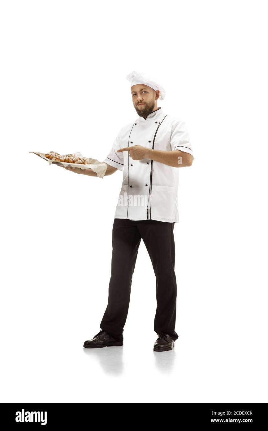 Cuisinière, chef, boulanger en uniforme sur fond blanc avec croissants. Jeune homme pleine longueur, portrait de cuisinière de restaurant. Affaires, la porte, l'occupation professionnelle, le concept d'émotions. CopySpace pour publicité. Banque D'Images
