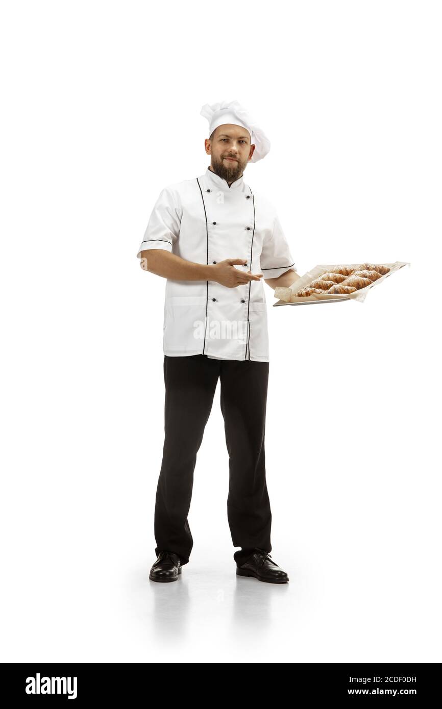 Cuisinière, chef, boulanger en uniforme isolé sur fond blanc studio avec croissants. Jeune homme, portrait de cuisinière de restaurant. Affaires, la porte, l'occupation professionnelle, le concept d'émotions. CopySpace pour publicité. Banque D'Images