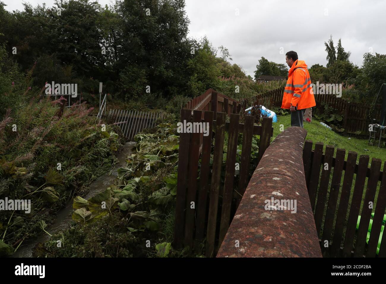 Un fonctionnaire du conseil examine un cours d'eau après une inondation à la cour de Pyothall à Broxburn, Lothian occidental. Banque D'Images