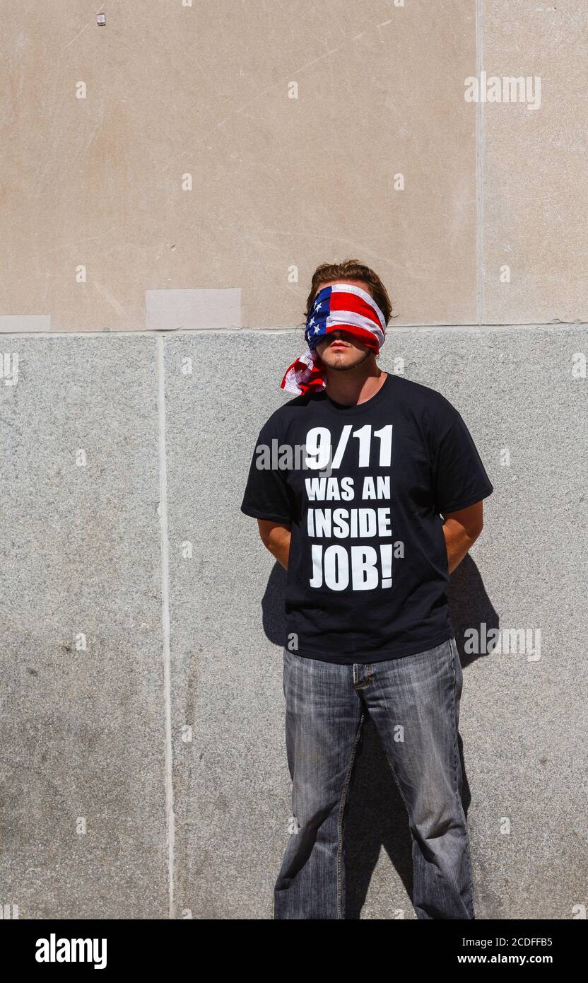 Un jeune homme américain se dresse sur le site du World Trade Center à New York, avec ses yeux bandés, portant un t-shirt noir sous la coupe : « 9/11 était un travail à l'intérieur ! » Banque D'Images