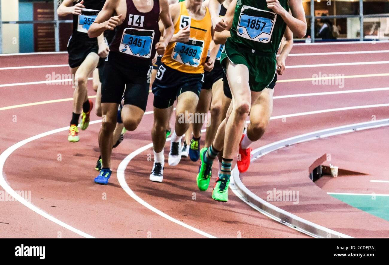 Beaucoup de mâles courir un mile sur une piste intérieure bancarisée lors d'une compétition sur piste et terrain. Banque D'Images
