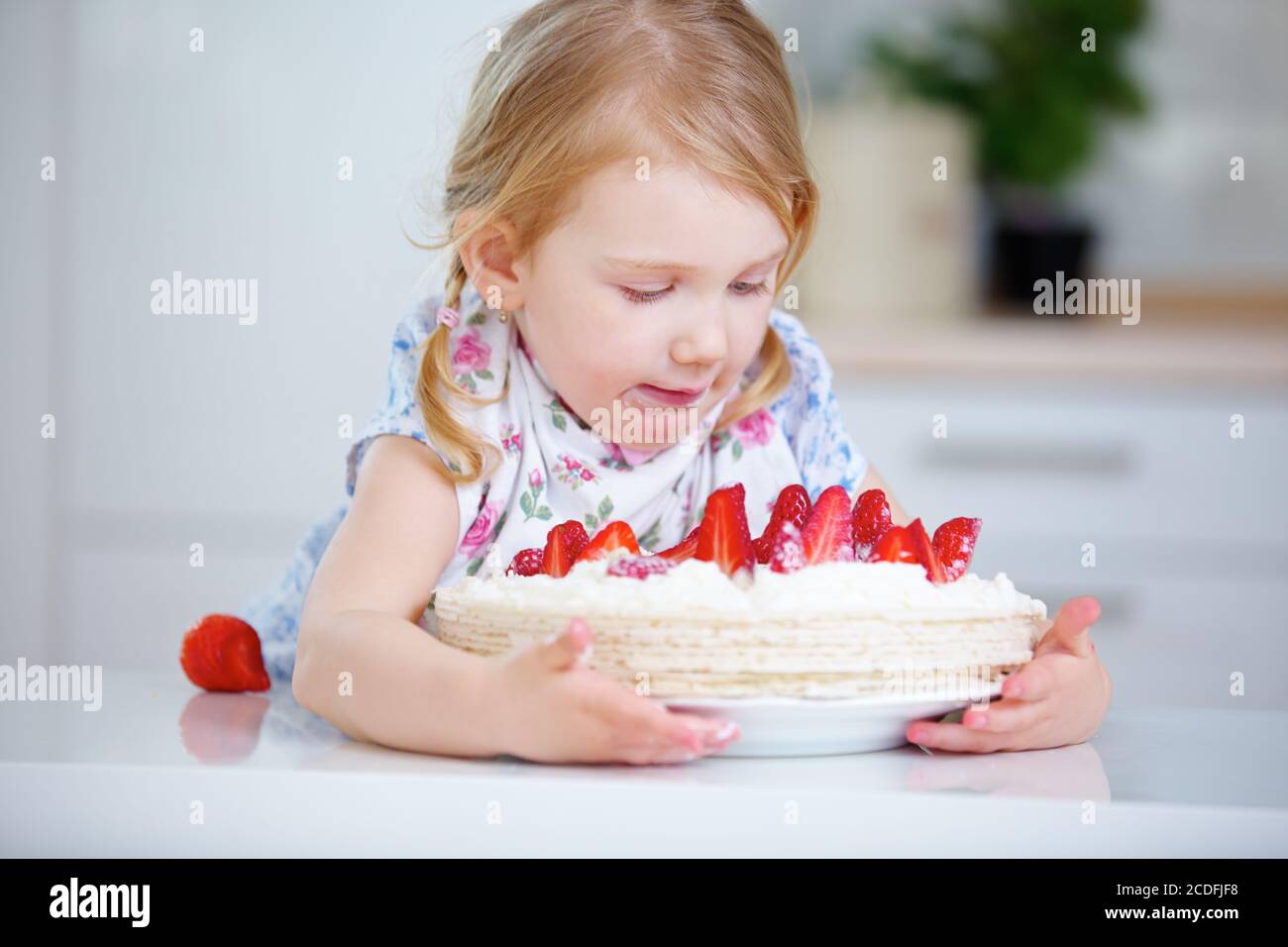 Bonne fille à l'anniversaire de l'enfant avec un gâteau frais Banque D'Images