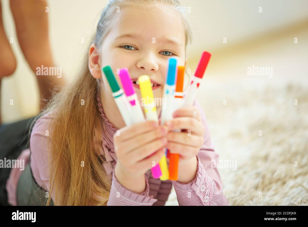 Fille souriante montre beaucoup de stylos colorés en elle mains Banque D'Images