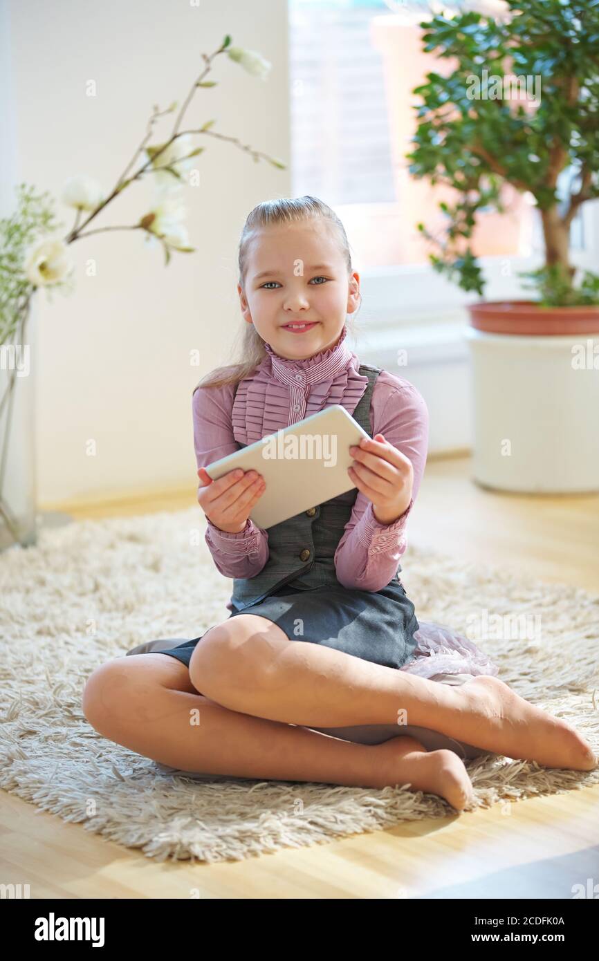 Une fille souriante joue avec une tablette à la maison Banque D'Images