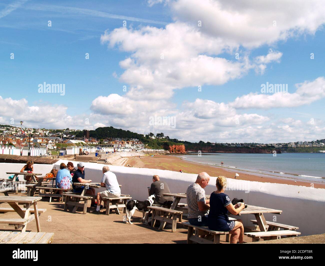 Les gens mangeant dehors avec la distanciation sociale étant observée regardant sur la plage de Preston Sands, Paignton, Torbay, sud-ouest de l'Angleterre. Banque D'Images