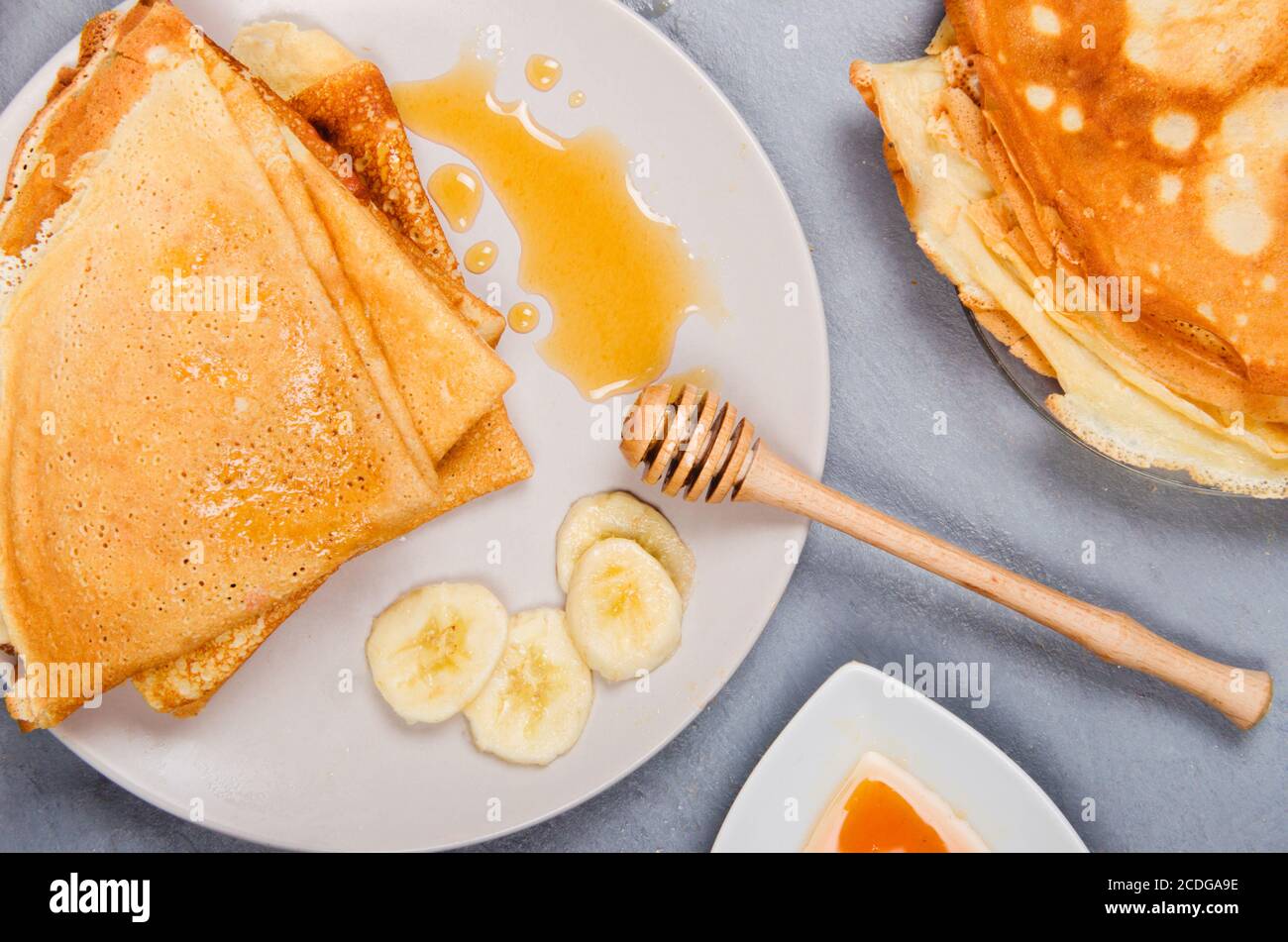 Crêpes avec bananes et miel pour le petit déjeuner sur table rustique blanche Banque D'Images