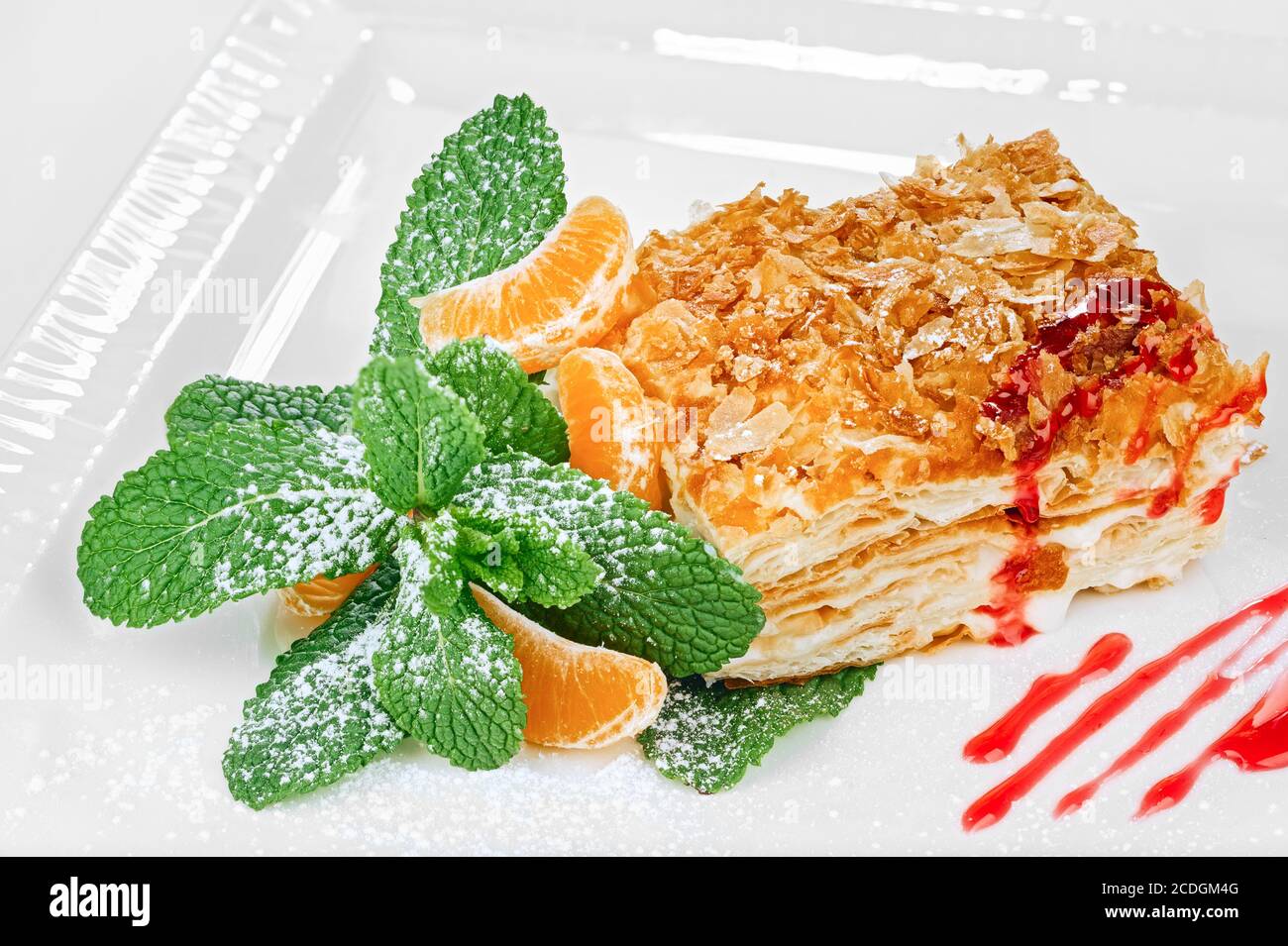 Dessert traditionnel napoléon (mille-feuille) avec feuilles de menthe, glaçage au sucre, tranches de mandarine et décoration de confiture isolée sur le backgro blanc Banque D'Images