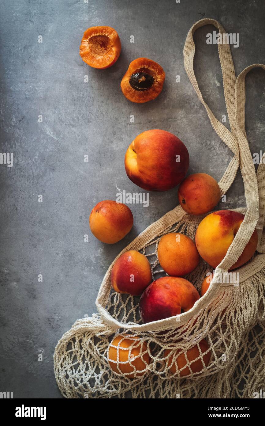 Aplatir avec des abricots frais de mûrissement dans un sac de marché un arrière-plan sombre Banque D'Images