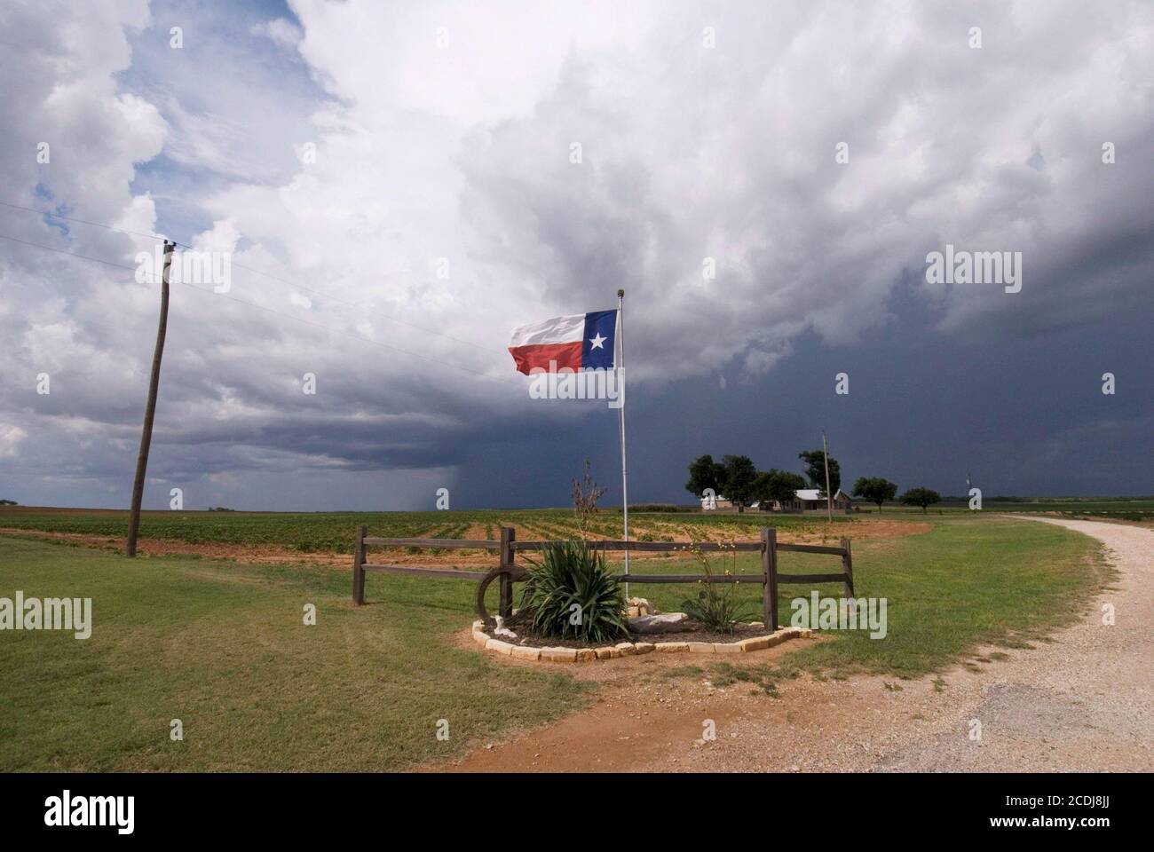 Mitchell County, TX le 26 juillet 2007 : des nuages de tempête traversent les plaines, lançant une brise raide sur le drapeau de l'État du Texas en volant à une entrée du ranch sur l'autoroute 208 du Texas entre Abilene et San Angelo. ©Bob Daemmrich Banque D'Images
