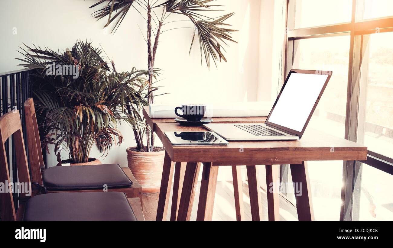 Travail de bureau avec ordinateur portable sur la table de bois contre les fenêtres. Banque D'Images