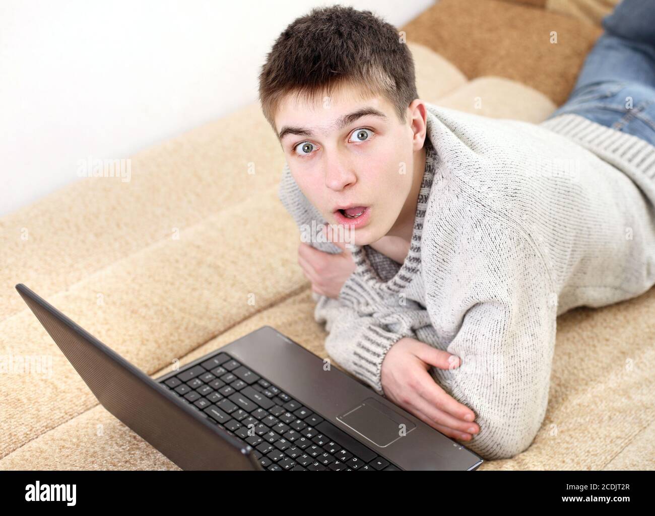 un adolescent stupéfié avec un ordinateur portable Banque D'Images