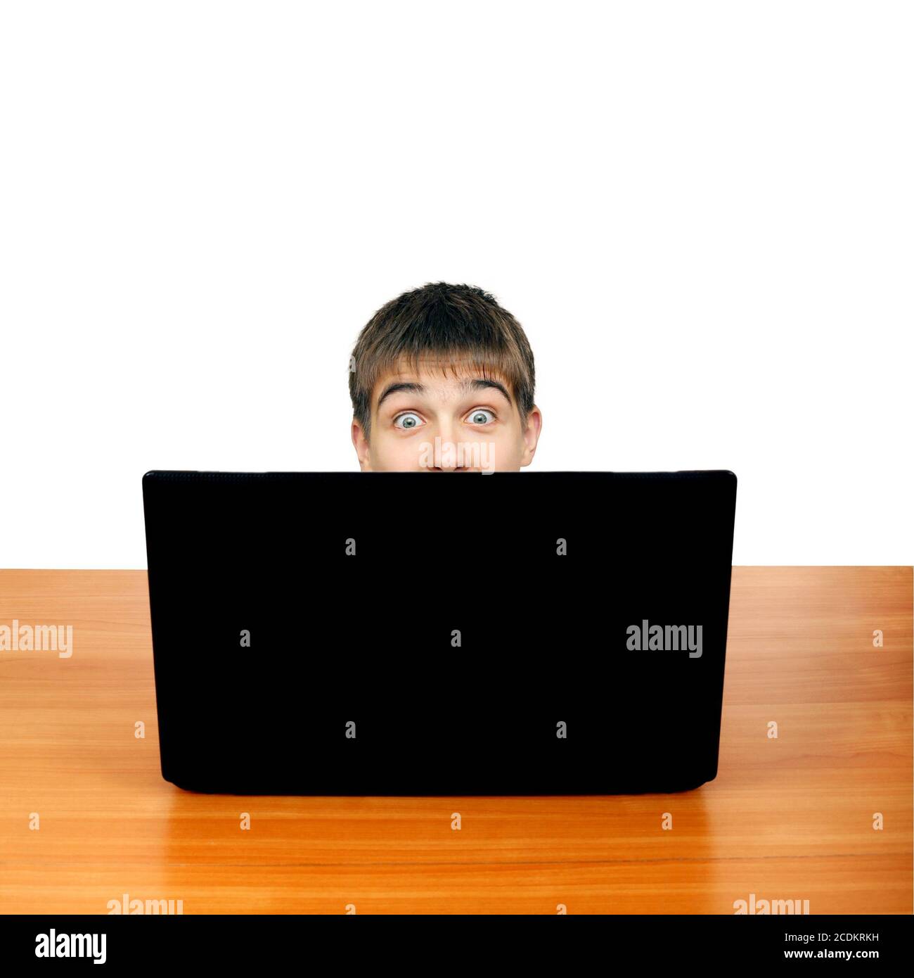 Un adolescent surpris derrière un ordinateur portable Banque D'Images