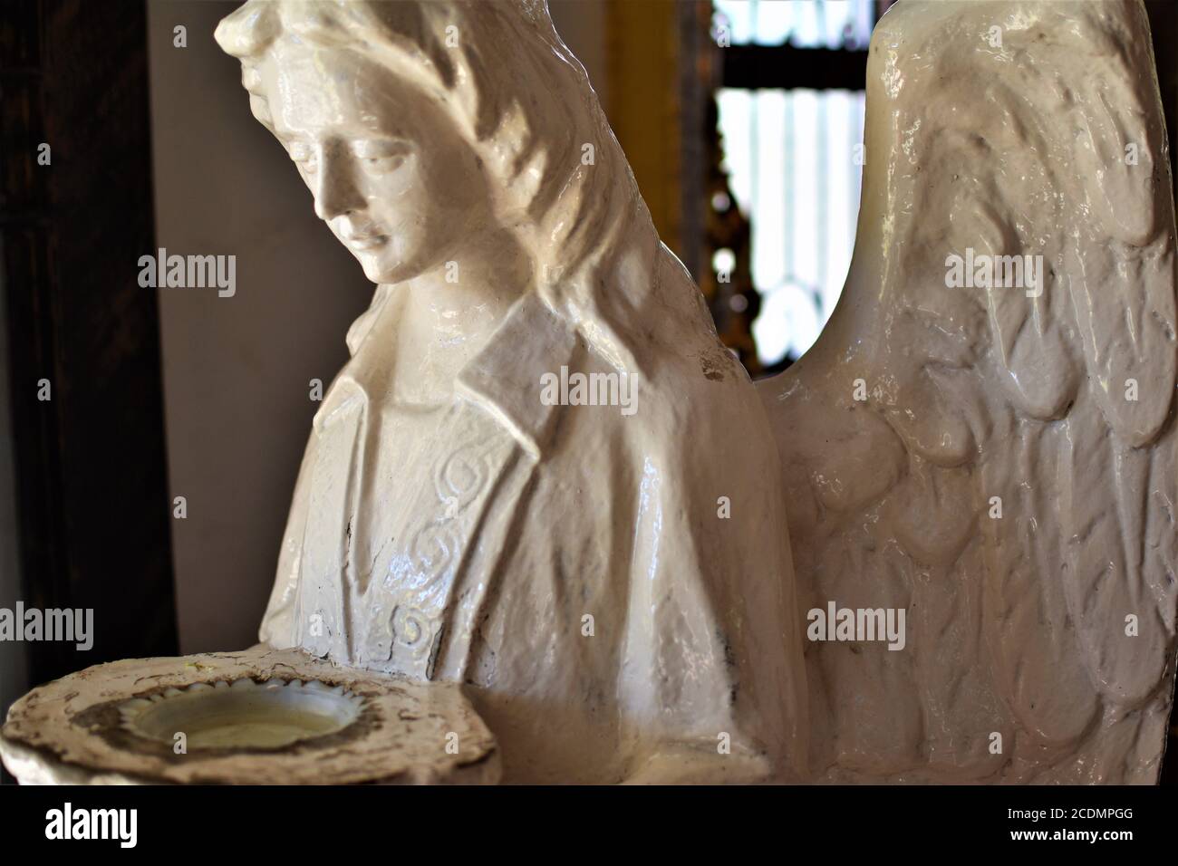 Une ancienne statue blanche d'un ange ailé tenant un saint-stoup d'eau Banque D'Images