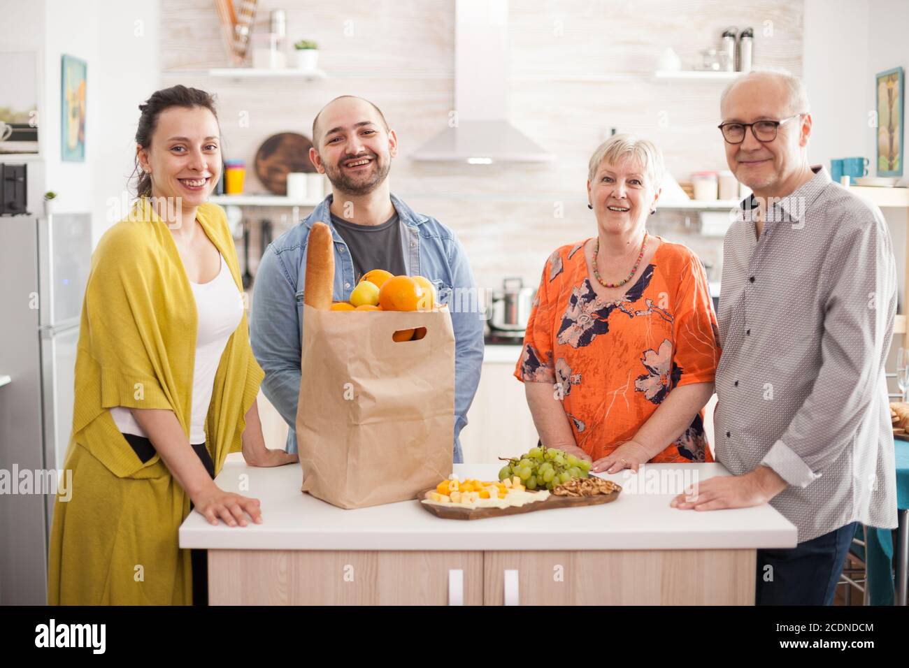 Une famille de plusieurs générations souriant en regardant l'appareil photo dans la cuisine. Banque D'Images
