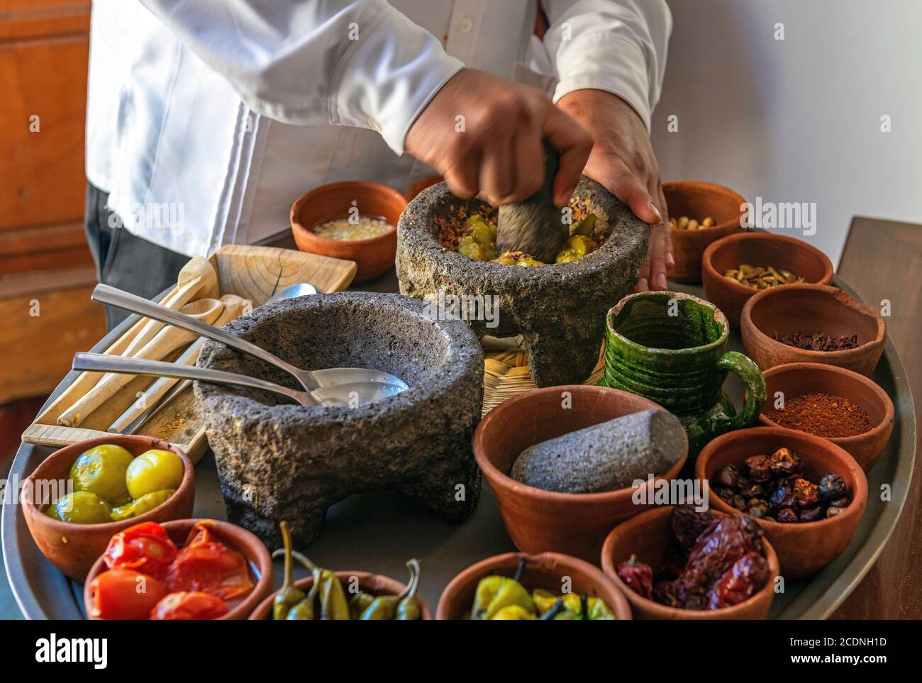 Chef préparant une sauce traditionnelle au Chili de Pasilla avec tous les ingrédients, Oaxaca, Mexique. Mise au point sur le mortier, flou de mouvement. Banque D'Images