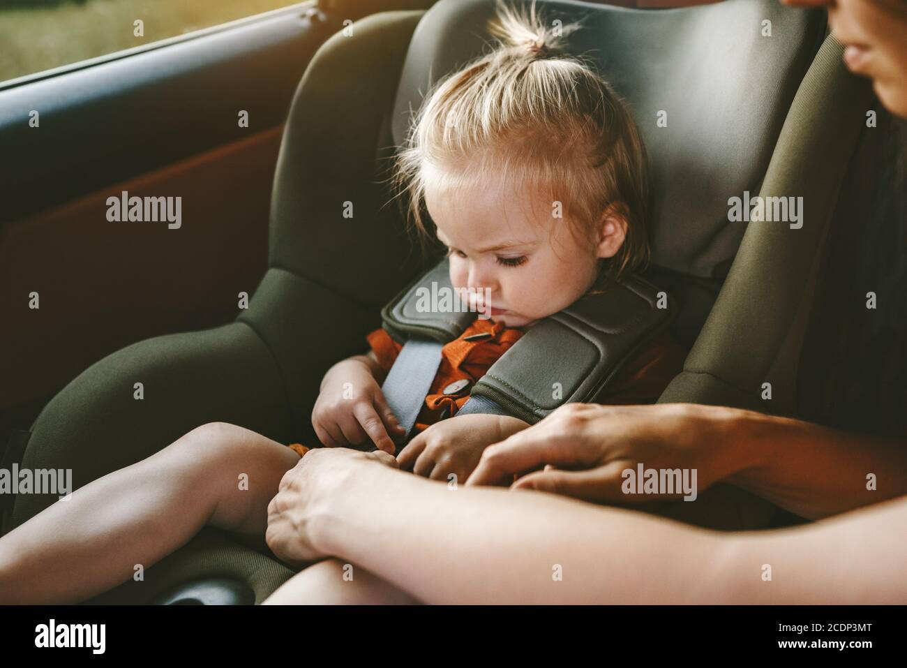 Enfant fille dans le siège de sécurité de voiture et la mère attache la ceinture voyage en famille vacances de style de vie avec le transport de sécurité de bébé Banque D'Images