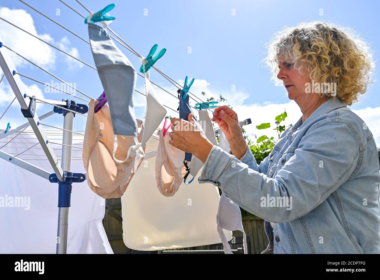 Masques lavables ou revêtements de visage à porter pendant le coronavirus COVID-19 pandémie accrochée sur une ligne de lavage à Brighton, Royaume-Uni Banque D'Images