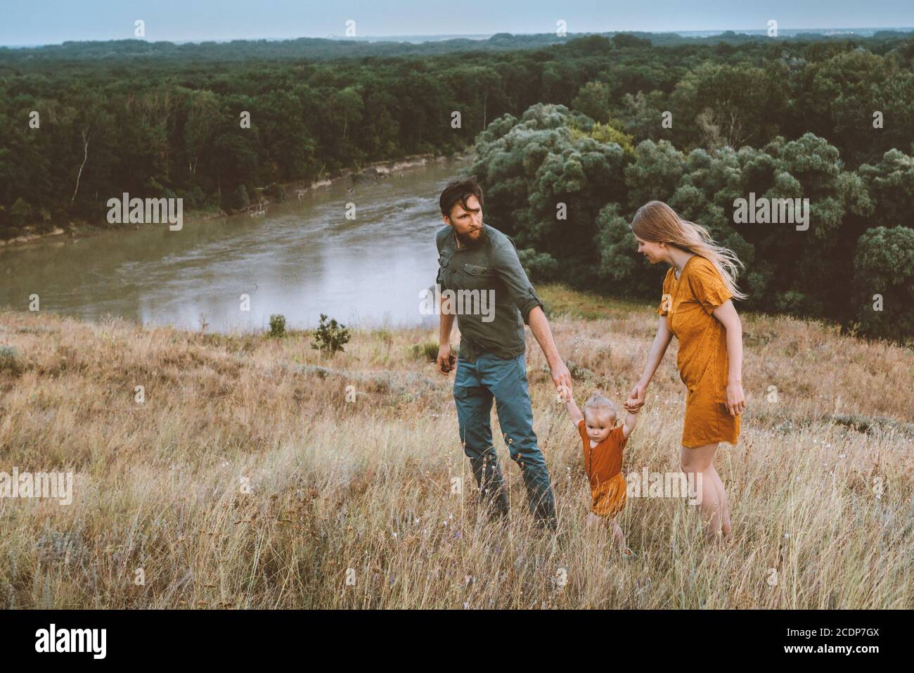 Parents de famille marchant avec bébé fille en plein air mère et père avec un style de vie sain pour les enfants nature rurale vue sur la rivière et la forêt Banque D'Images