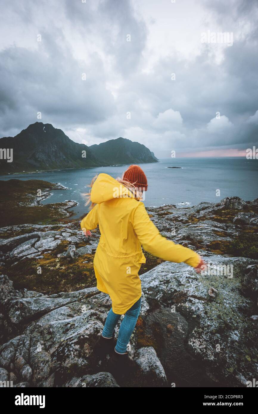 Femme en imperméable jaune marchant dans les montagnes de Norvège vacances actives Aventure en plein air saine mode de vie fille seule explorer les îles Lofoten venteux r Banque D'Images