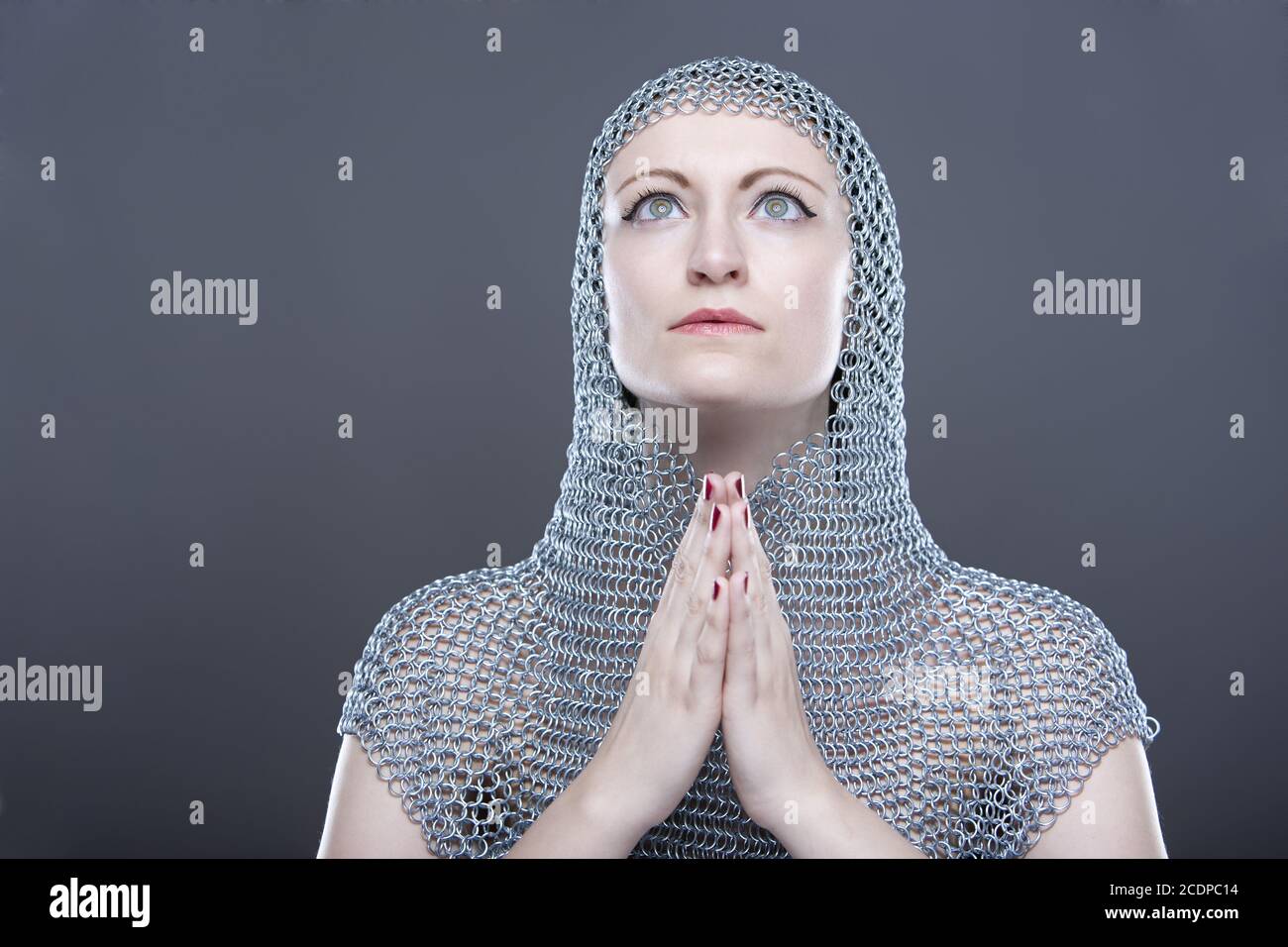 Jeune femme avec cagoule de chainmail médiéval avec les mains pliées Banque D'Images