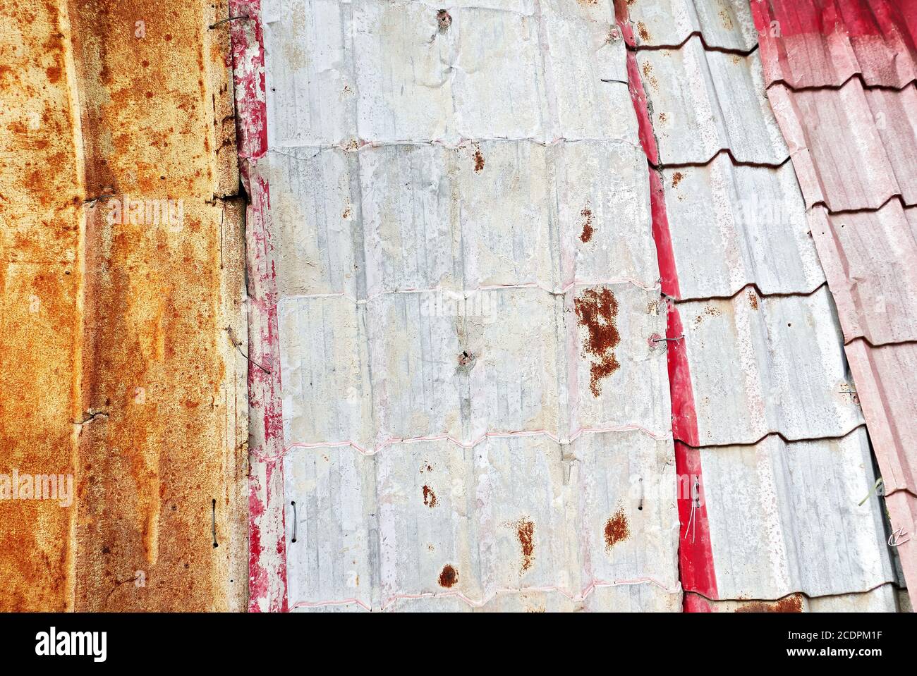 Vue détaillée des anciennes tôles rouillées et peintes utilisées comme toiture, maintenues avec des fils métalliques seulement, souvent vues en Asie Banque D'Images