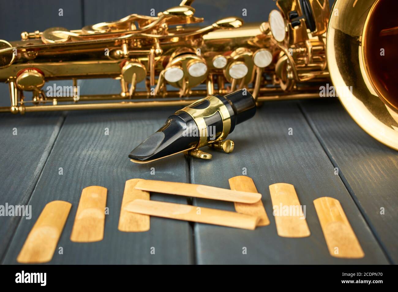 embout buccal saxophone avec pince métallique et matériel de réglage doré,  avec roseaux de rechange et corps d'instrument sur fond en bois gris Photo  Stock - Alamy