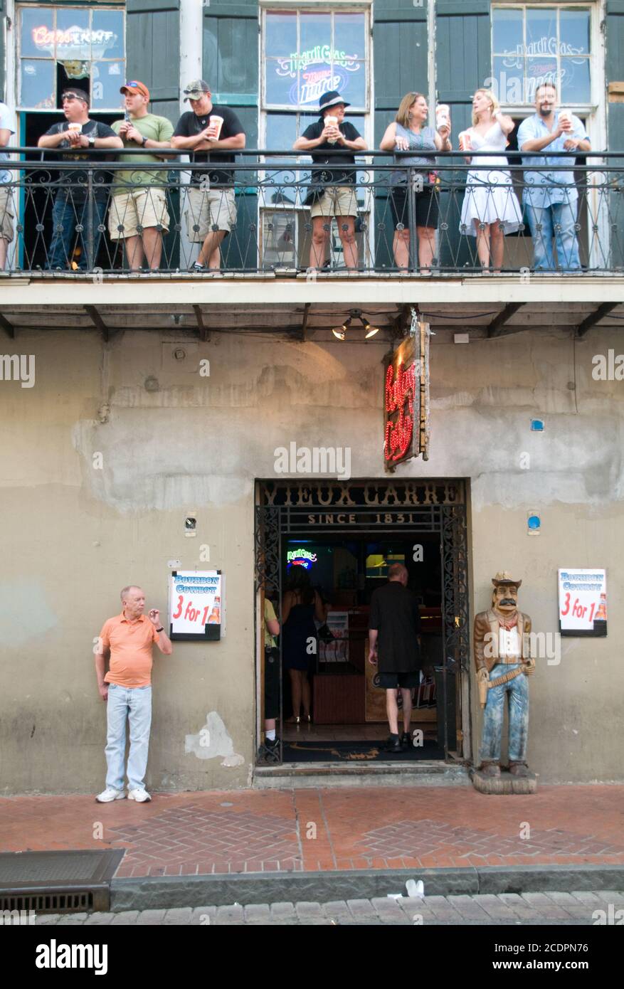 Les clients buvant sur le balcon au-dessus de l'entrée d'un bar dans le quartier français de la Nouvelle-Orléans, Louisiane, États-Unis Banque D'Images