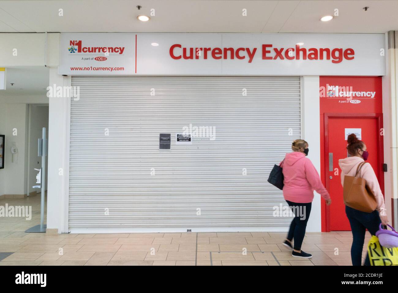 Les femmes avec masque facial passent devant un magasin de change fermé en raison de la pandémie de coronavirus, ashford, kent, royaume-uni Banque D'Images