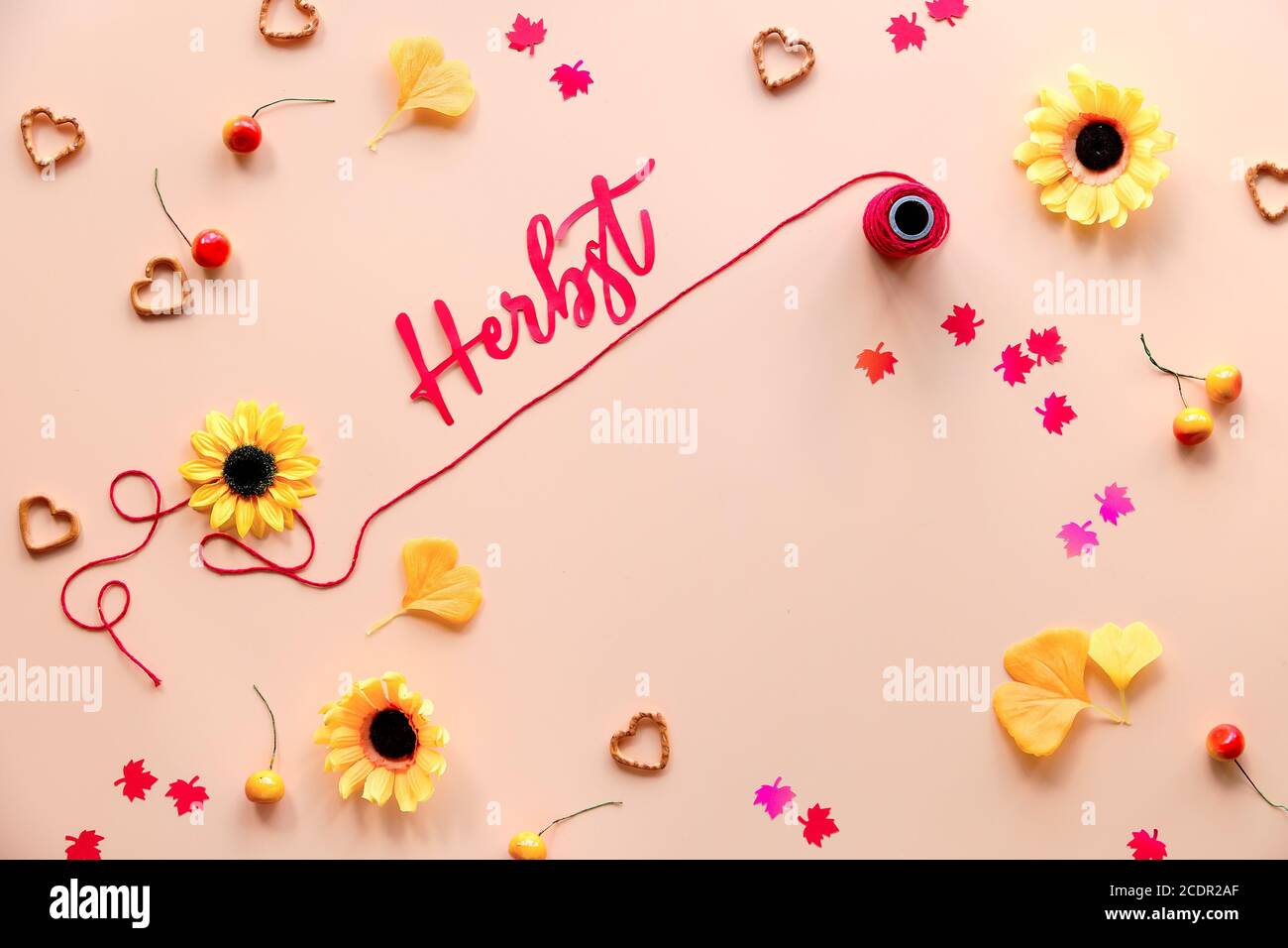 Herbst signifie automne en allemand. Plat saisonnier sur fond orange. Décorations d'automne - fleurs, feuilles d'érable et de gingko, confettis en papier, baies an Banque D'Images