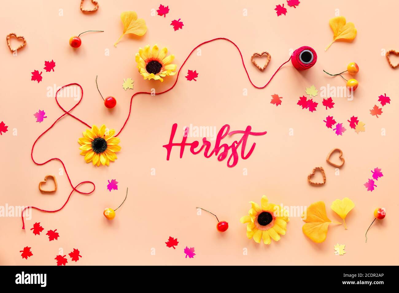 Plat saisonnier sur fond orange. Herbst signifie automne en allemand. Décorations d'automne - fleurs, feuilles d'érable et de gingko, confettis en papier, baies an Banque D'Images