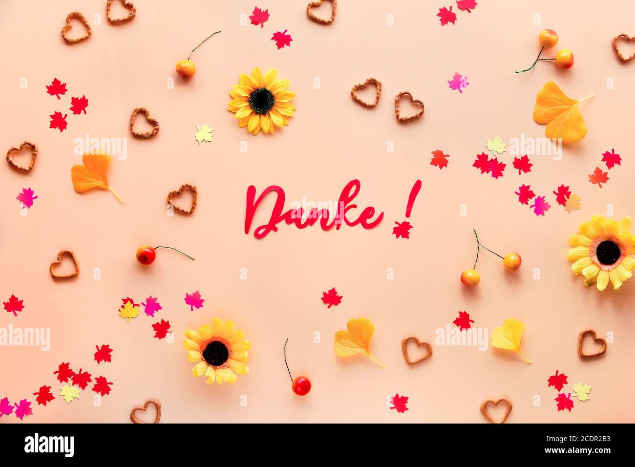 Danke signifie Merci en allemand. Décorations d'automne - fleurs, feuilles d'érable et de gingko, confettis en papier, baies et bretzels en forme de coeur. Automne plat la Banque D'Images