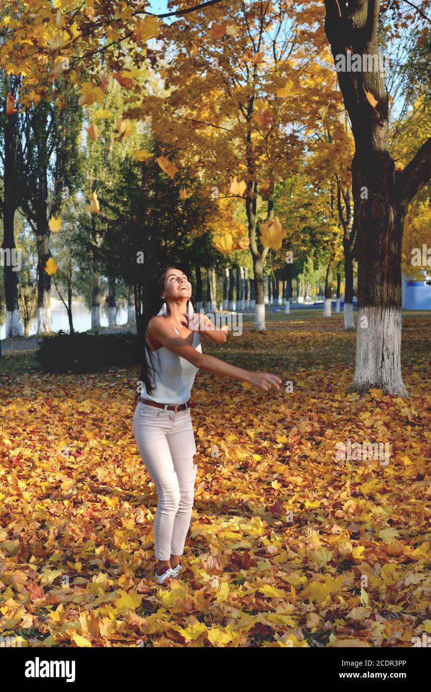 fille jeta des feuilles d'automne jaunes, des ordres et des pièces dans le parc, jour ensoleillé, sourire, rire et bonne humeur, gros plan Banque D'Images