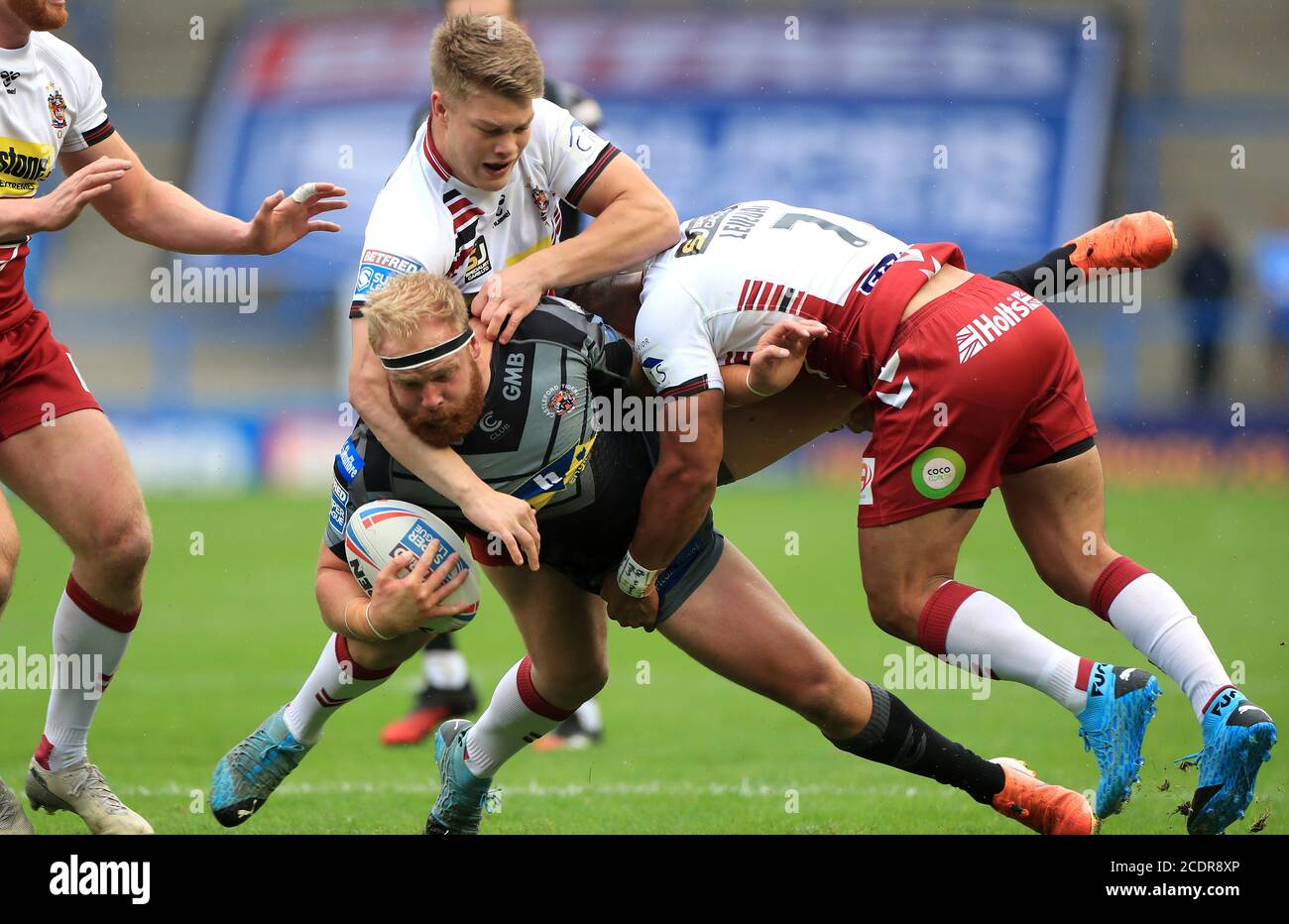 Oliver Holmes (au centre) de Castleford Tigers est affronté par Morgan Smithies (à gauche) de Wigan Warriors et Thomas Leuluai lors du match de la Super League au stade Halliwell Jones, à Warrington. Banque D'Images