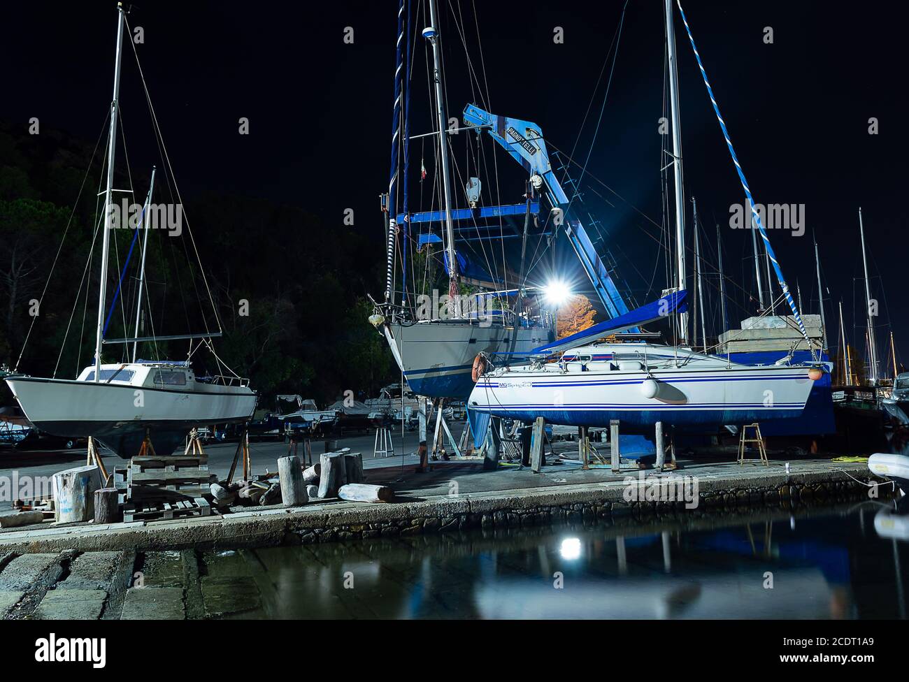 Cagliari, Sardaigne, Italie - août 28 2020 : levée de bateau hors de l'eau par une grue lourde dans la jetée de la ville la nuit Banque D'Images