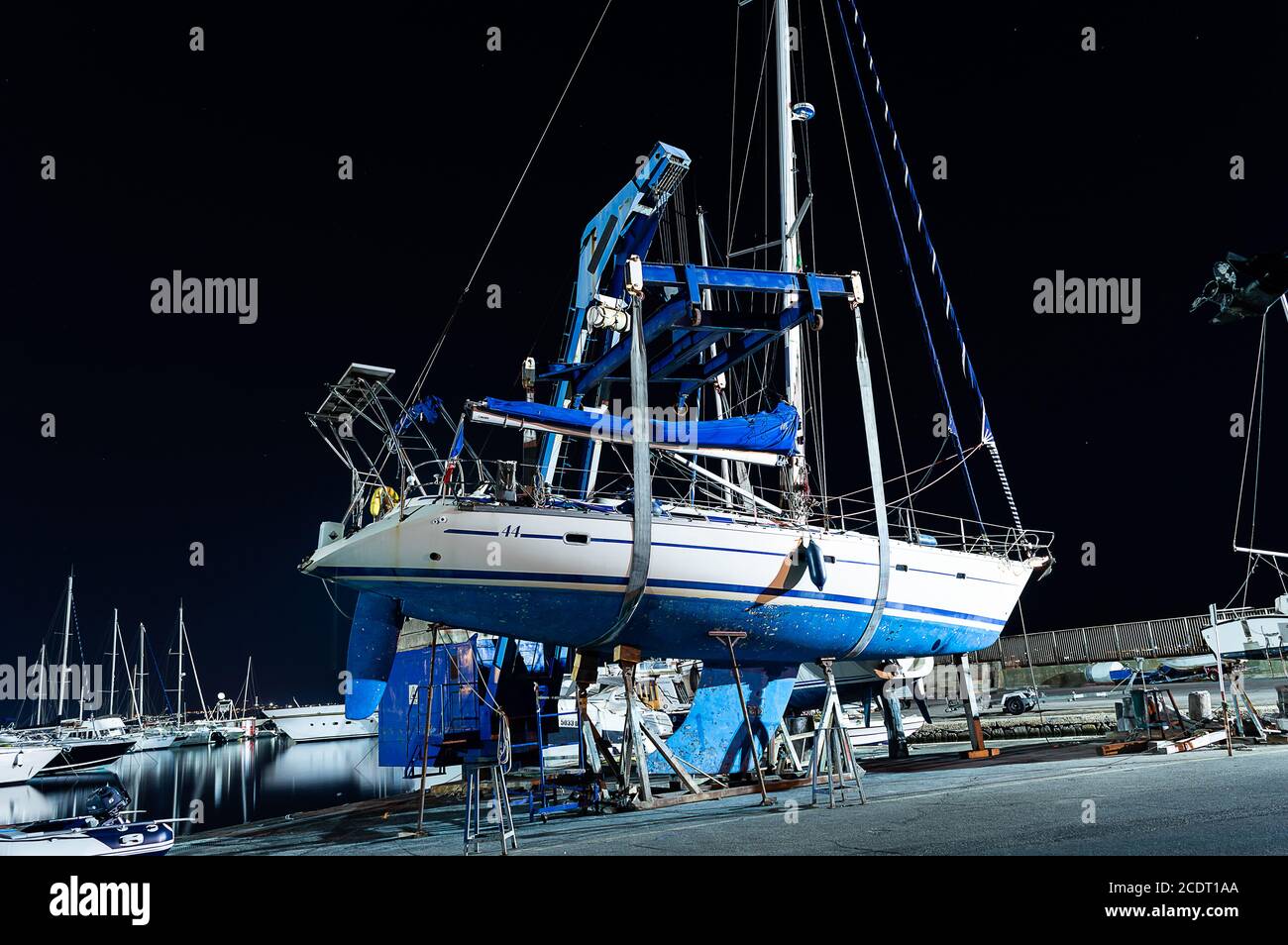 Cagliari, Sardaigne, Italie - août 28 2020 : bateau-ascenseur hors de l'eau par une grue lourde dans la ville jetée vue latérale la nuit Banque D'Images