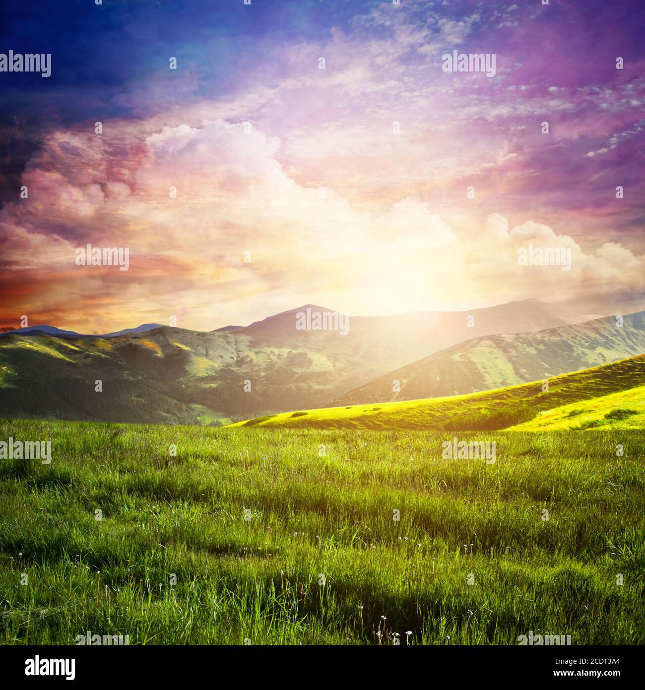 Paysage de conte de fées avec herbe verte, montagnes, coucher de soleil ciel fantastique. Banque D'Images