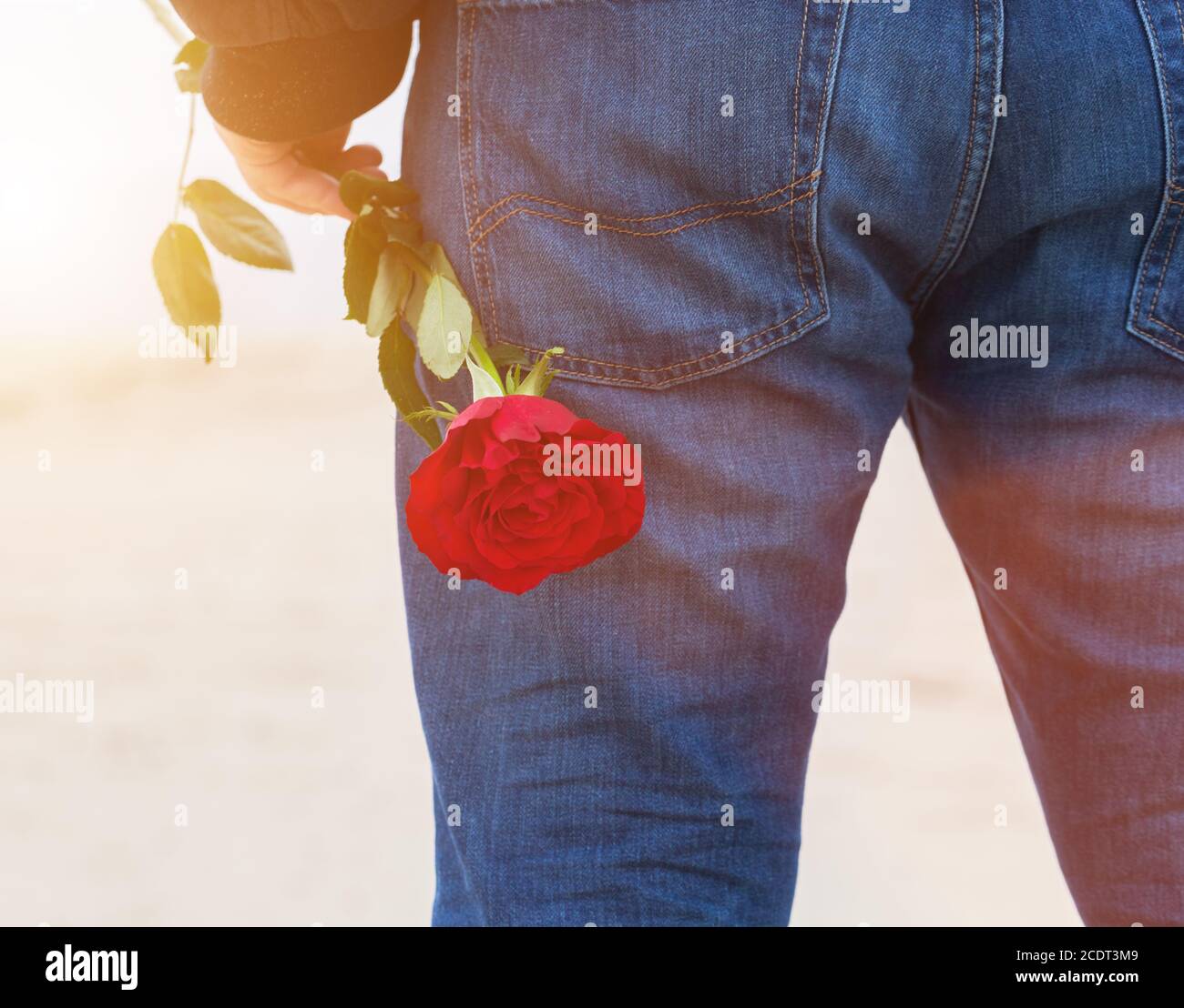 Homme avec une rose derrière son dos attendant l'amour. Romantique date sur la plage Banque D'Images