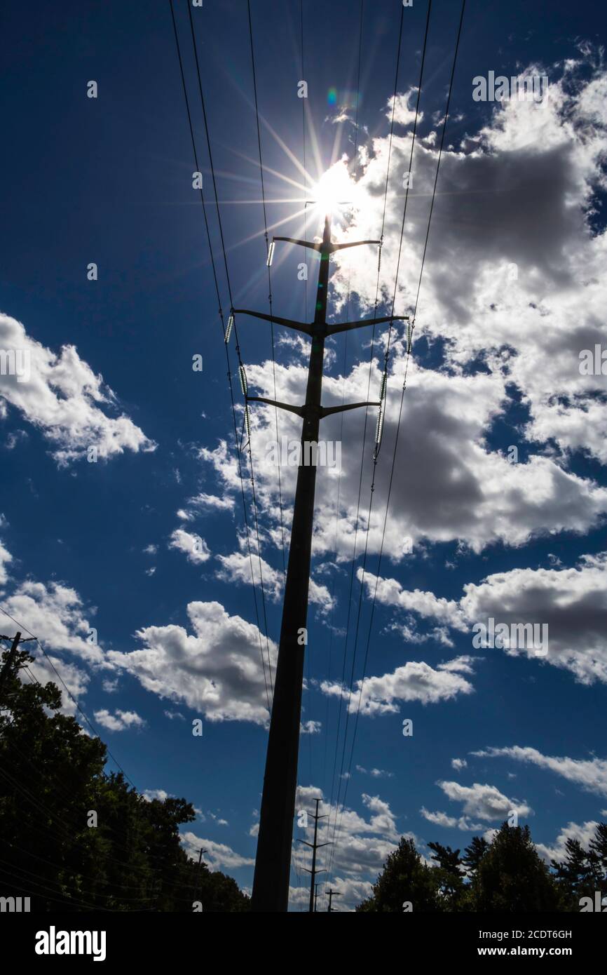 Sunburst au sommet d'une tour de ligne électrique avec nuages et soleil en arrière-plan Banque D'Images