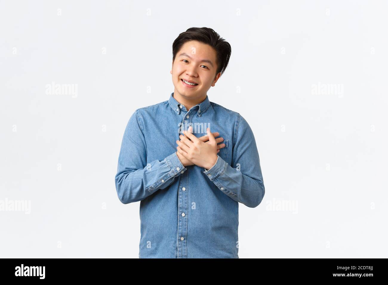 Jeune homme d'affaires asiatique plein d'espoir et heureux commençant sa propre startup, tenant les mains sur le cœur comme reconnaissant pour les investissements de personnes, prenant soin de clients Banque D'Images