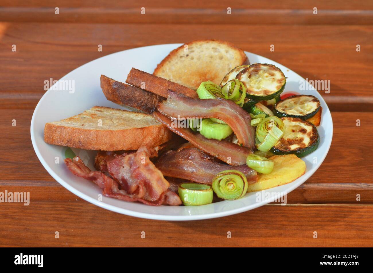 Assiette de légumes grillés, bacon et pain sur table en bois, barbecue Banque D'Images