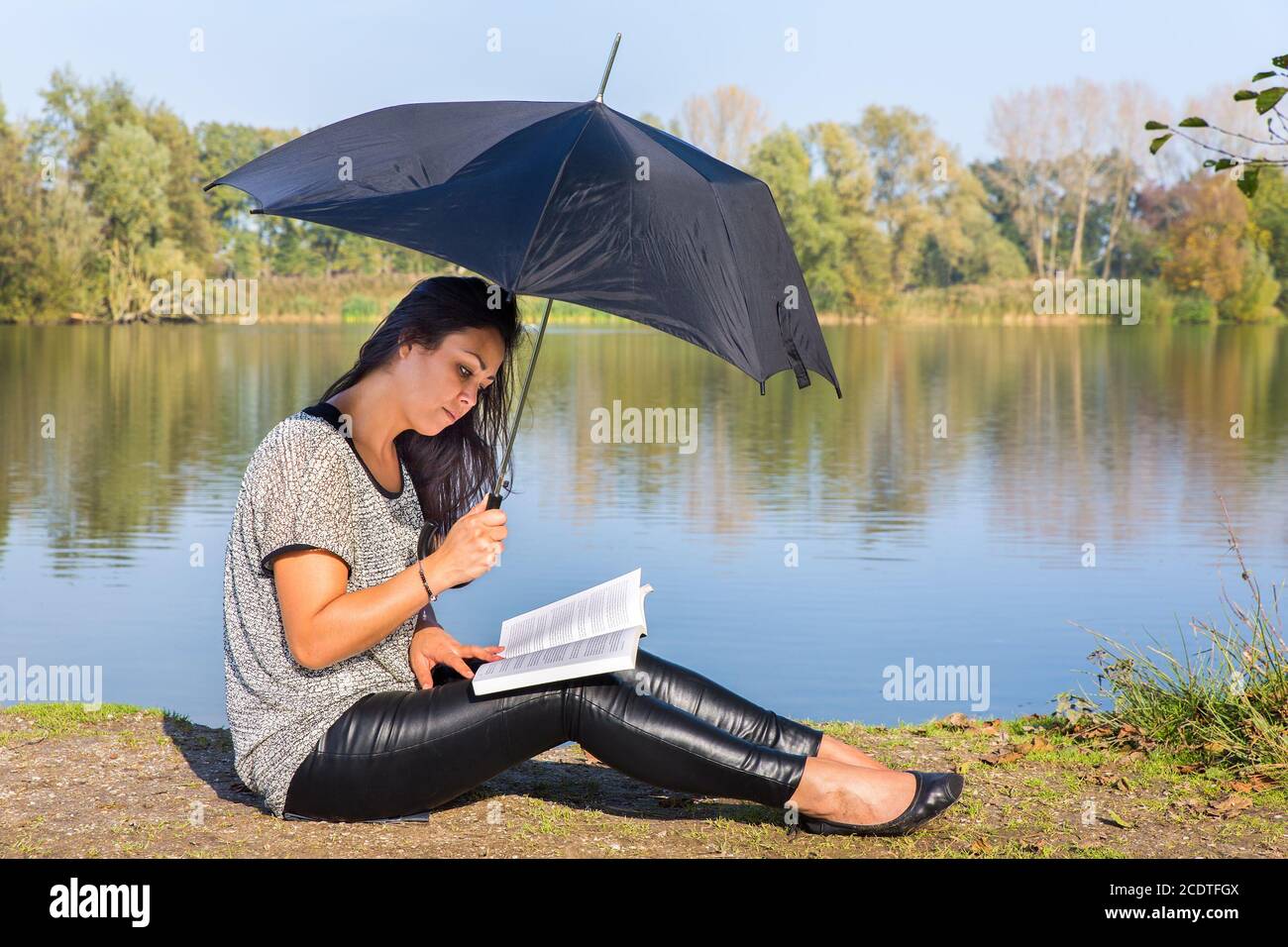 Femme avec un livre de lecture de parapluie dans la nature Banque D'Images