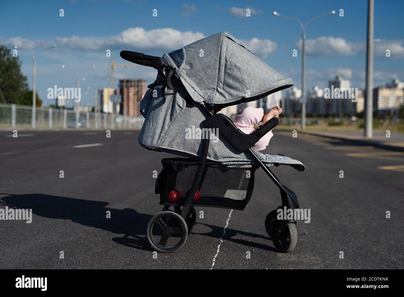 Le Porte Bebe Gris Est Debout Sur Le Reservoir Les Jambes De Bebe Sont Visibles Du Chariot Photo Stock Alamy