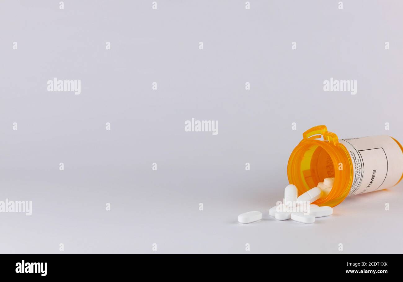 flacon de pilule couché sur le côté avec des comprimés blancs déborder sur un arrière-plan blanc avec l'espace de copie dans format paysage Banque D'Images
