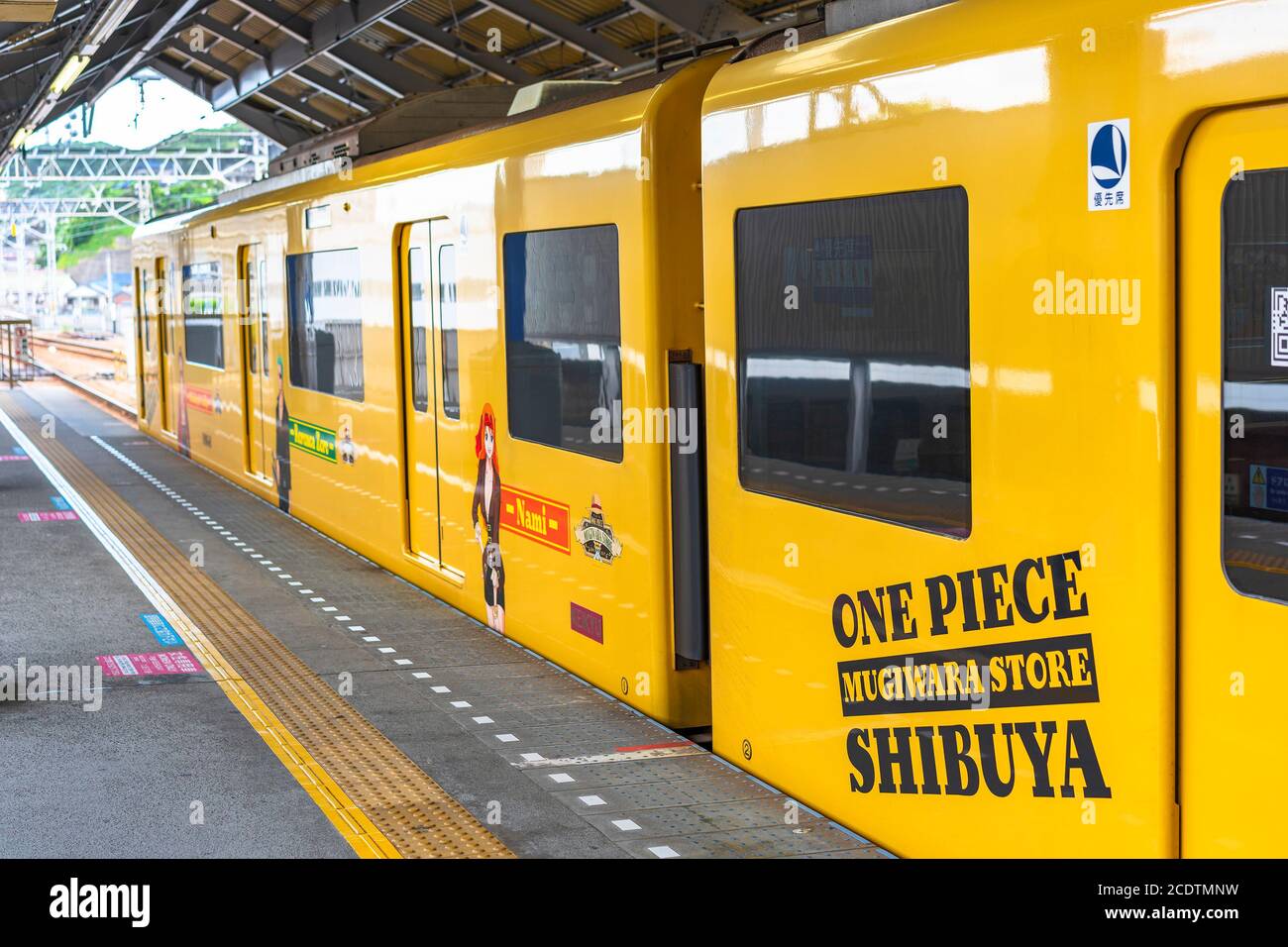 kanagawa, japon - juillet 19 2020: Train jaune de la ligne de Yokosuka enveloppé d'autocollants publicitaires de manga et de personnages d'anime Nami, Zoro et Luffy pour Banque D'Images