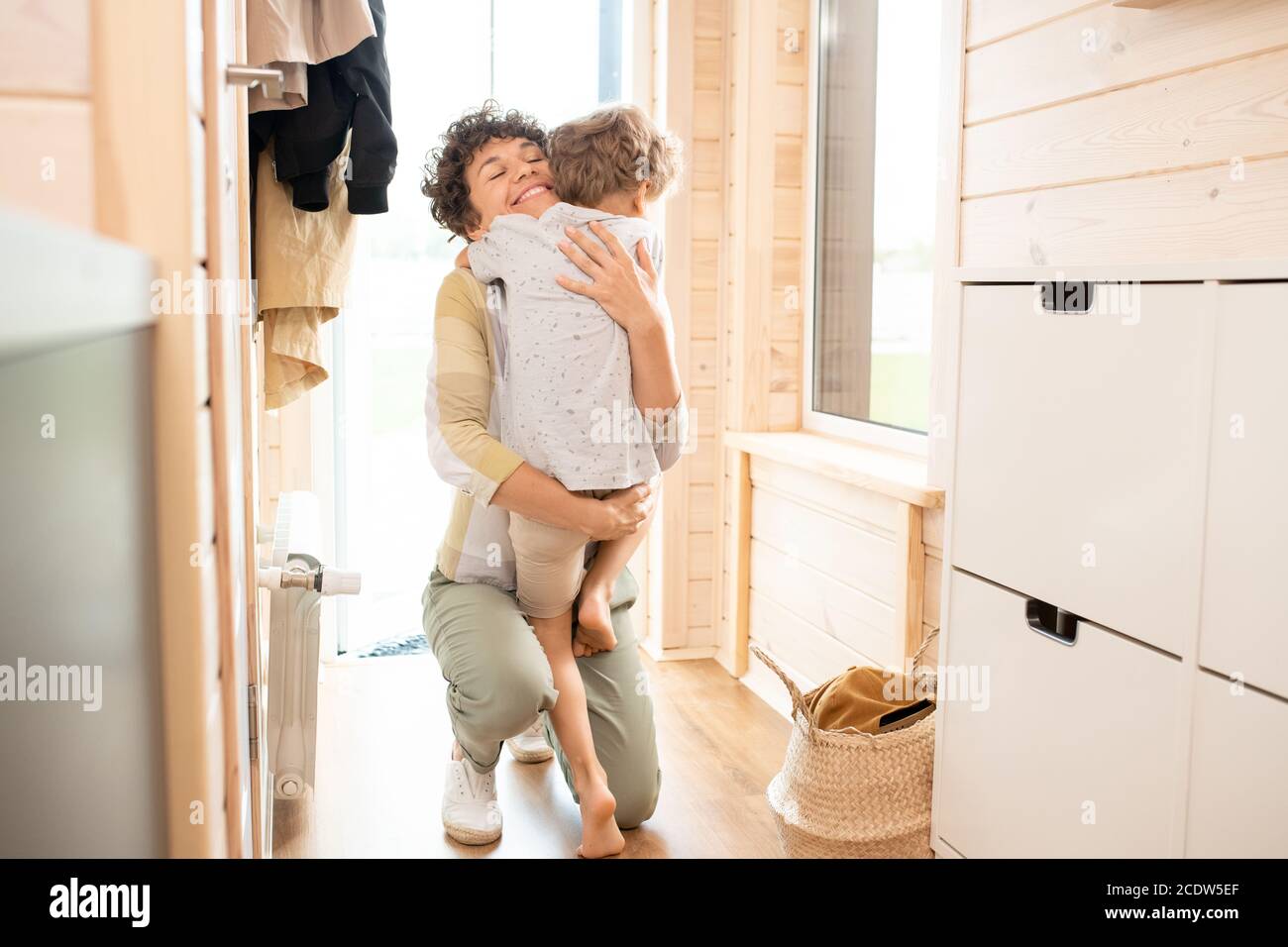 Une jeune mère embrasse son petit fils mignon après son retour la maison au travail Banque D'Images